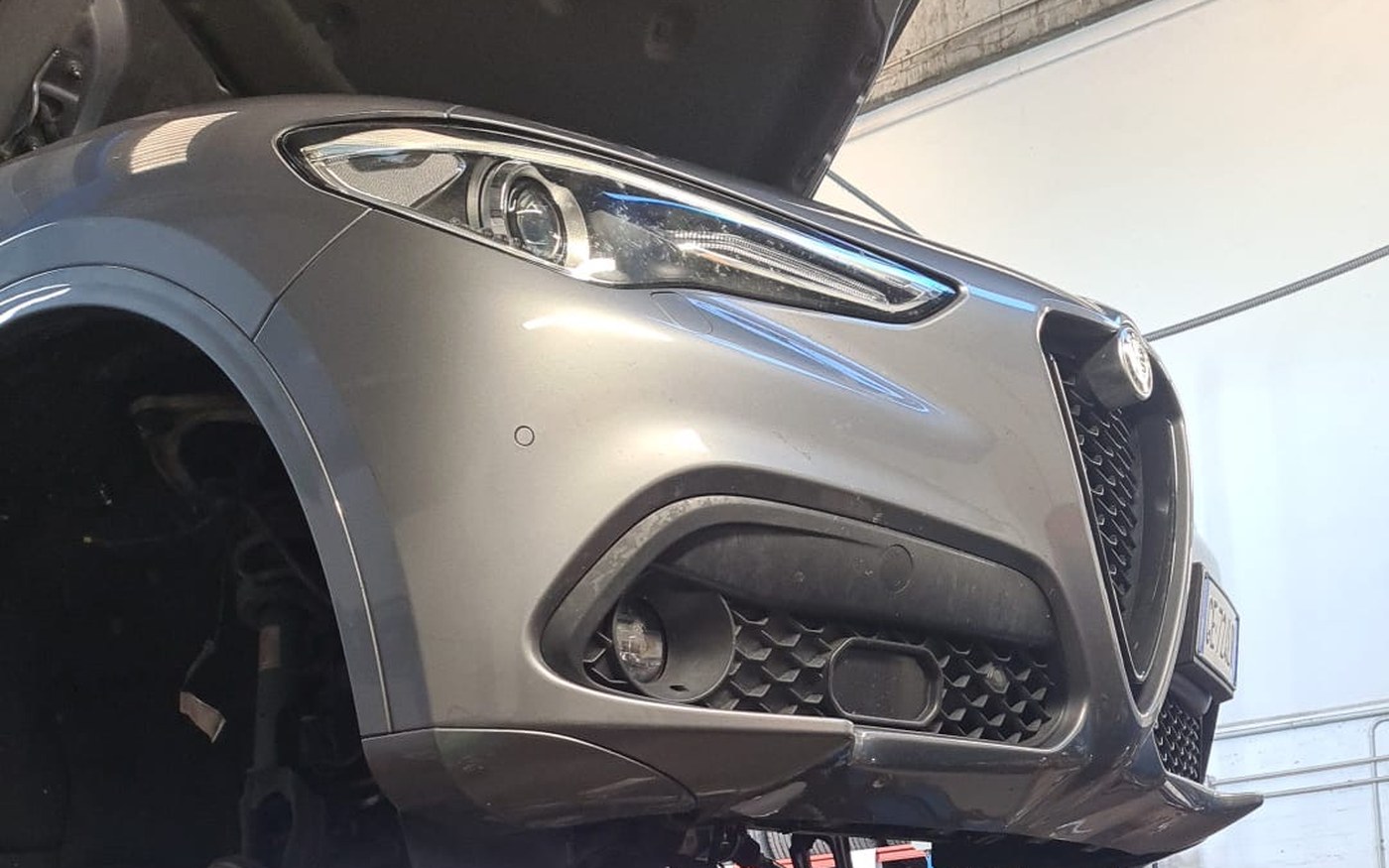 Alfa Romeo Stelvio sollevata sul ponte dell'officina per un controllo al motore
